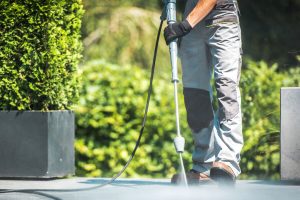 Patio Pressure Cleaning. Caucasian Men Washing His Concrete Floor Patio Using High Pressured Water Cleaner.
